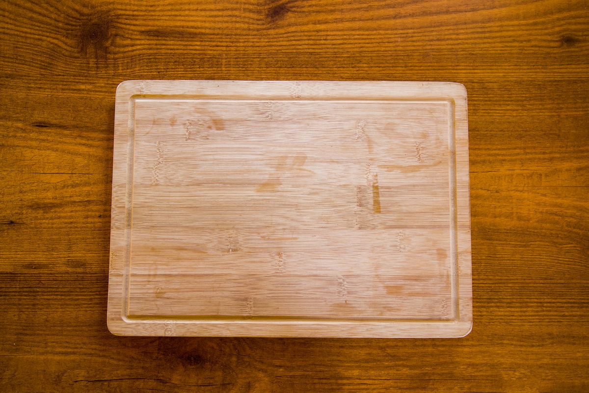 Natural bamboo cutting board with kitchen utensils